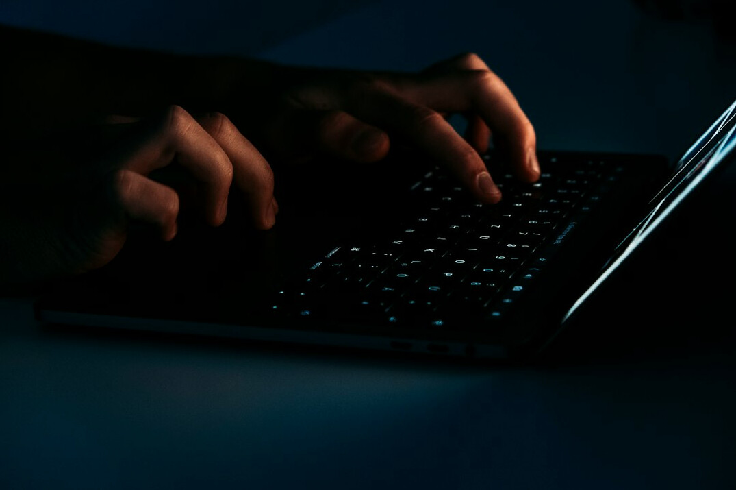 Young man writing code on a laptop at a desk